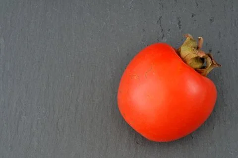 Persimmon on slate plate, flat Stock Photos