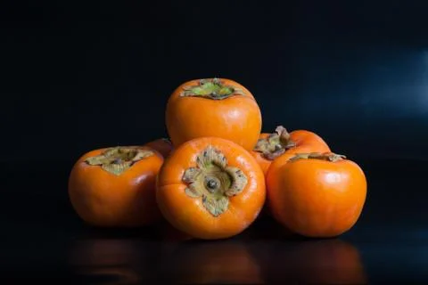 Persimmons on black reflective background Fotos de archivo
