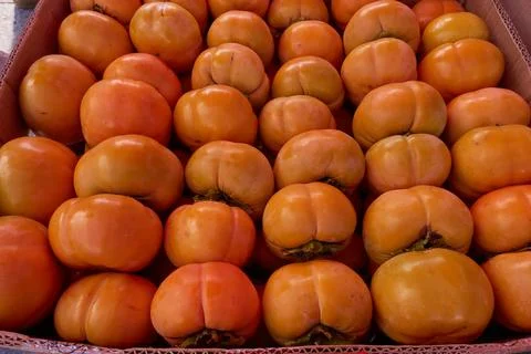 Persimmons in boxes on the market. Stock Photos