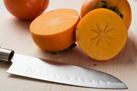 Persimmons on cuttingboard Stock Photos