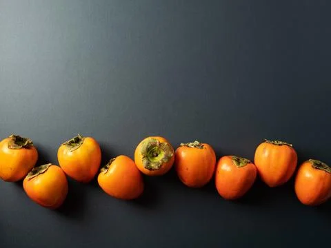 Persimmons on a dark background Stock Photos