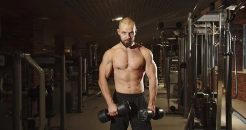 A persistent athlete pumps up his arms with dumbbells with a small weight Stock Footage 205515368