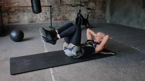 Persistent lady works on abs lying on black mat in gym Video stock 211084669