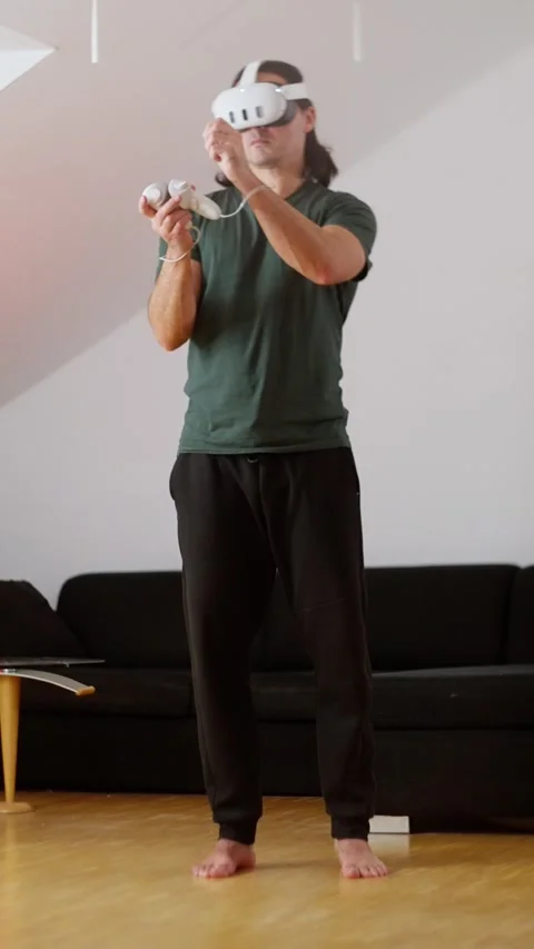 A person is actively engaged in playing a virtual reality game in the comfort of Stock Footage 302658174