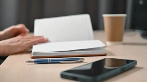 A person is actively turning the pages of a notebook while taking notes with a Stock Footage 339005831