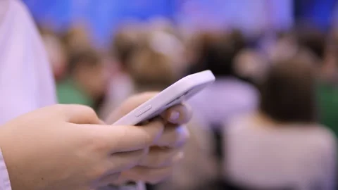 A person actively utilizing a smartphone during a conference vividly underscores Vídeos de archivo 299002241