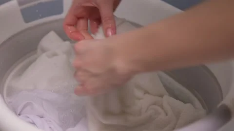 A Person Actively Washing Clothes While Using a Modern Washing Machine for Stock Footage 307442584