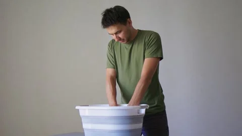 A Person Actively Washing Clothes While Using a Modern Washing Machine for Stock Footage 312265362