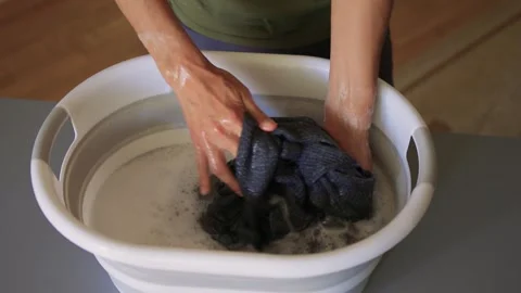 A Person Actively Washing Clothes While Using a Modern Washing Machine for Stock Footage 312265523