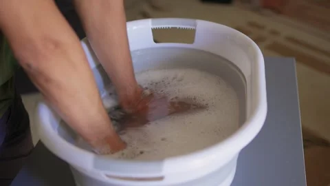 A Person Actively Washing Clothes While Using a Modern Washing Machine for Stock Footage 312265538