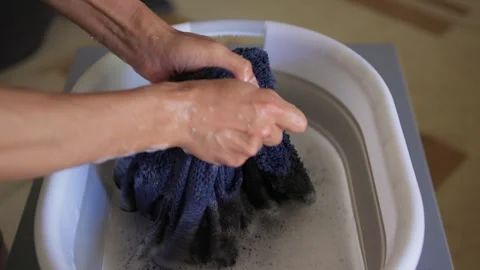A Person Actively Washing Clothes While Using a Modern Washing Machine for Stock Footage 312265569
