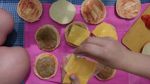 Person Adding Cheese Slice to Homemade Beef Burgers During Outdoor Picnic 库存影片 341998986
