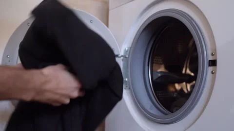 Person adding dark clothes to the washing machine Stock Footage 287688267