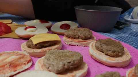 Person Adding Fresh Cheese Slice on Burger Patty During Outdoor Picnic 库存影片 341998637