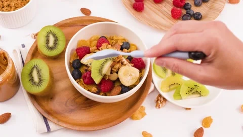 Person Adding Fresh Kiwi Slices to a Healthy Yogurt Breakfast Bowl Stock Footage 337519124