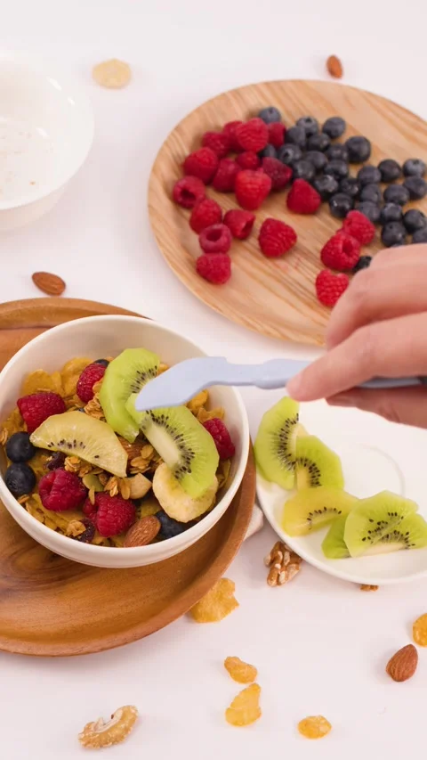 Person Adding Fresh Kiwi Slices to a Healthy Breakfast Yogurt Bowl Stock Footage 337519475