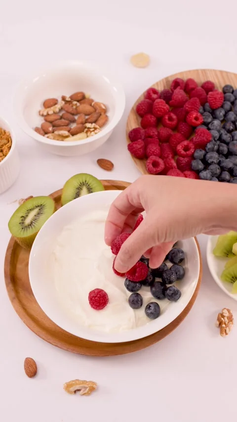 Person Adding Fresh Red Raspberries to a Greek Yogurt Breakfast Bowl Stock Footage 337925688