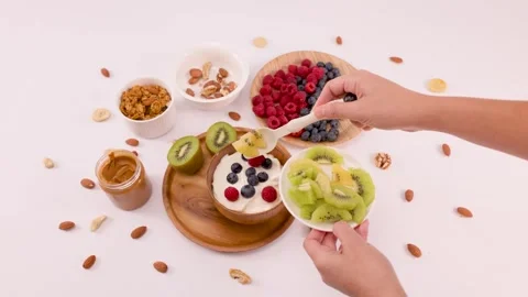 Person Adding Fresh Sliced Kiwi to a Healthy Yogurt Breakfast Bowl Stock Footage 337757882