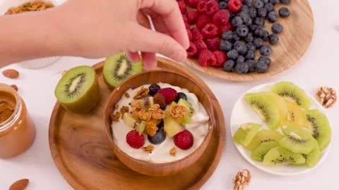Person Adding Granola and Nuts to a Healthy Yogurt Fruit Bowl Stock Footage 337757859