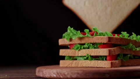 Person adding a slice of fresh bread to a large sandwich. Stock Footage 223513533