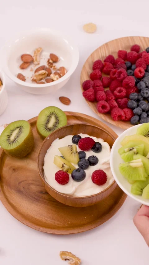 Person Adding Sliced Kiwi to a Healthy Yogurt Breakfast Bowl Stock Footage 337875678