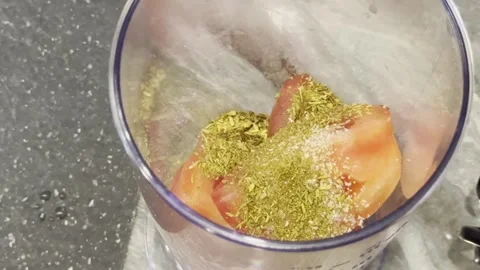 A person is adding spices to a blender full of food Stock Footage 283488245