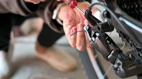 Person adjusting bicycle gear cable with screwdriver close up detail a Stock Footage 331902403