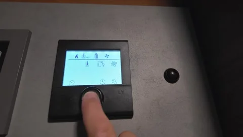 Person adjusting digital thermostat control panel in a campervan Vidéo 339178116