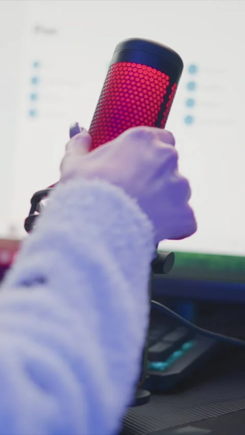 Person Adjusting Red Microphone with Keyboard and Computer Monitor in Indoor Stock Footage 345976252