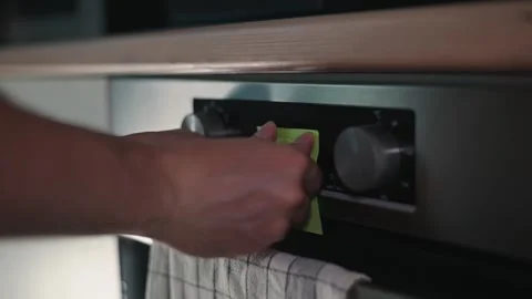 A person is adjusting the timer on an oven while placing a sticky note nearby Stock Footage 339096706