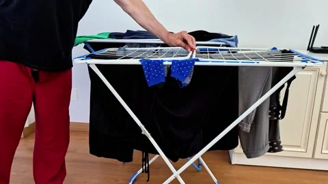 Person Adjusts Clothes on Indoor Foldable Drying Rack Stock Footage 338317580