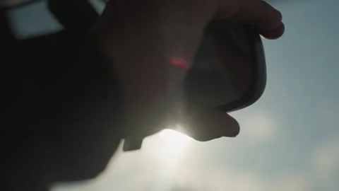 Person adjusts driver mirror to block sun flare on window Stock Footage 310182620