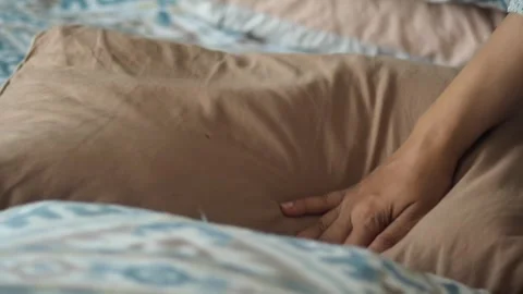 Person adjusts pillow on bed with patterned duvet slow motion comfort and r.. Stock-Footage 332897665