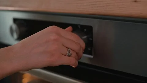 A person adjusts the temperature dial on an oven while preparing to bake. The Video stock 339094686
