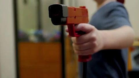 Person Aiming Red Arcade Light Gun at Shooter Game Screen Stock Footage 324803029