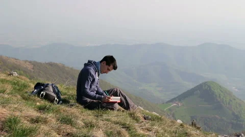 Person alone writes in his diary on top of the mountain Stock Footage 54286993