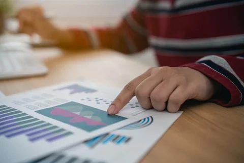 Person analyzing business chart report data with finger pointing on graph p.. Stock Photos
