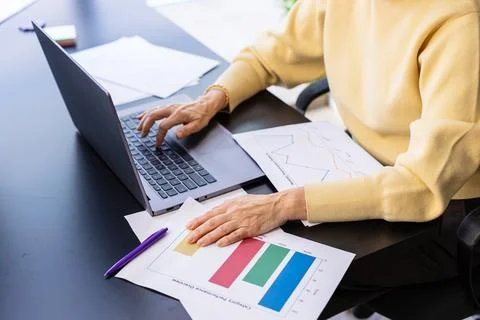 Person analyzing business data graphs using laptop at office desk Stock Photos