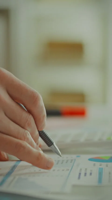 Person analyzing data and taking notes at a desk in a bright workspace envir Stock Footage 331671055