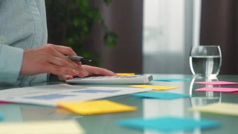 Person Analyzing Financial Data with Calculator and Graphs Video stock 313359251