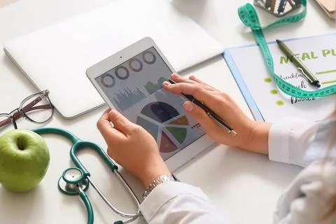 Person analyzing health data on tablet with medical tools nearby Stock Photos