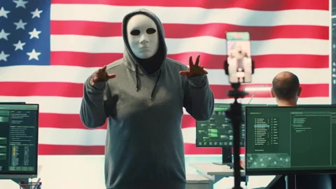 Person in anonymous mask working on intelligence in a governmental hacking room Stock Footage 277669097