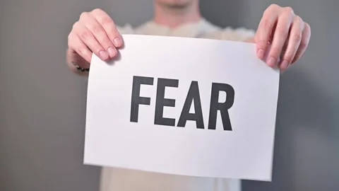 A person appears to be demonstrating an idea of overcoming fear by tearing a Stock Footage 338299831