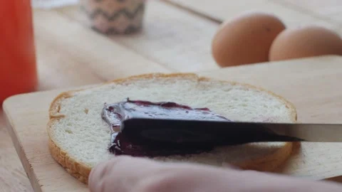 Person applying blueberry jam on slice of toast bread, breakfast food meal or Stock Footage 142136204