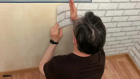 Person applying decorative brick wall covering during home renovation process in Stock Footage 335188852
