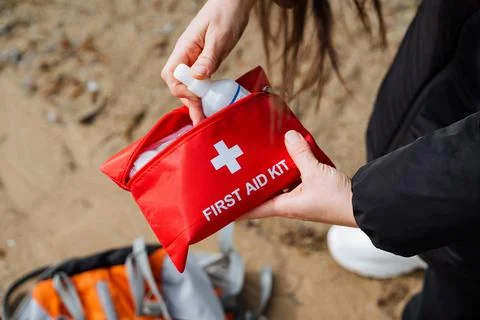 Person applying first aid using red first aid kit at outdoor location. Prep.. Foto stock