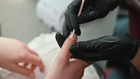 A person is applying nail care techniques using various tools in a close-up Stock Footage 339093688