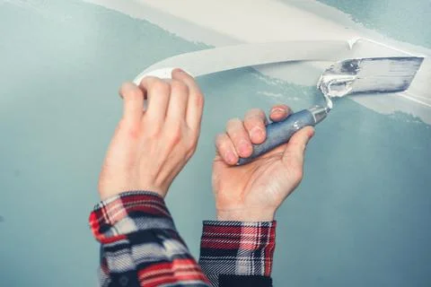 A Person Applying Patch to the Ceiling With a Roller in a Freshly Remodeled.. 스톡 사진