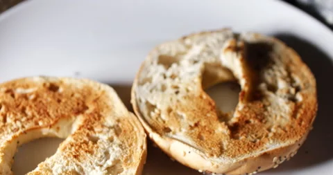 Person applying spread or butter to a toasted bagel Stock Footage 153759697