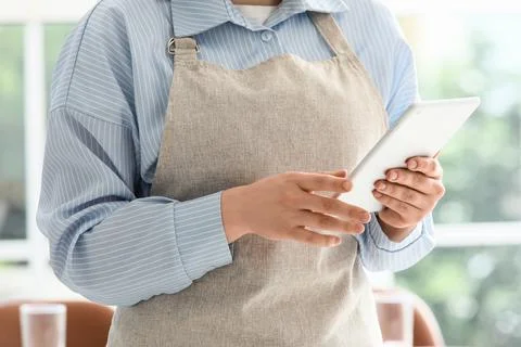 Person in apron using digital tablet indoors Stock Photos